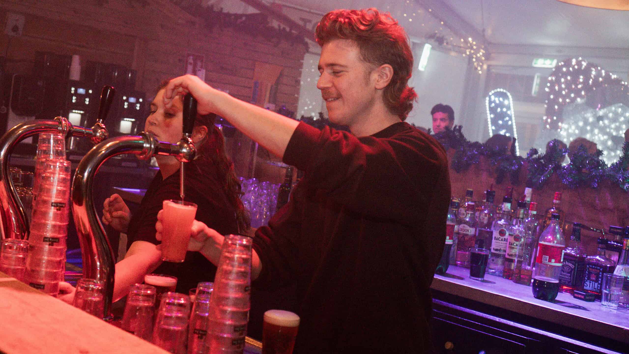 Barman serveert drankjes aan klanten.